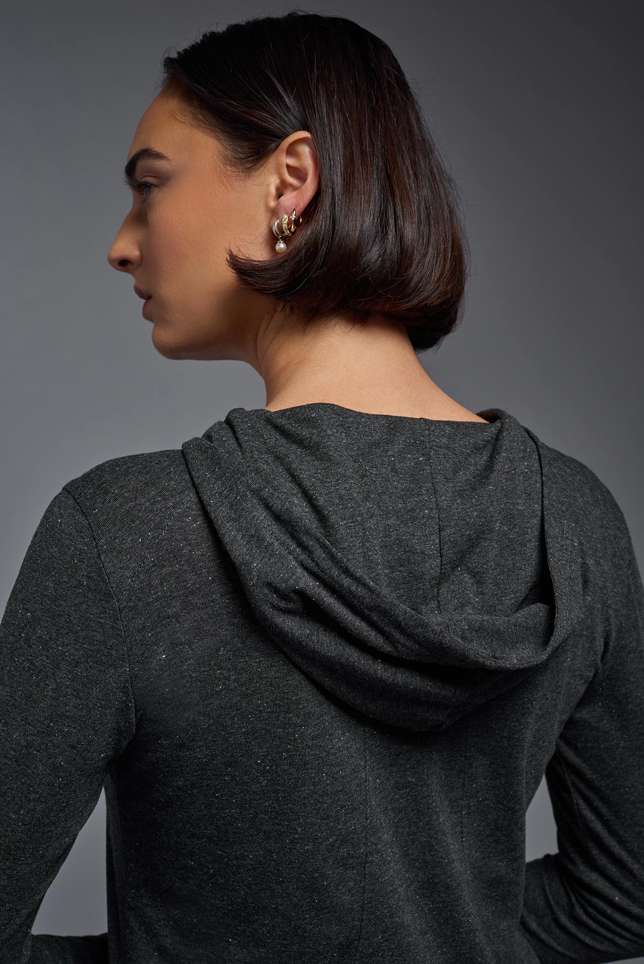 A female model wearing the women's Heather Hoodie Shirt in the color dark heather charcoal, showing the modern fit from a closeup hoodie back view. This hoodie shirt is made in the USA. #color_dark-heather-charcoal