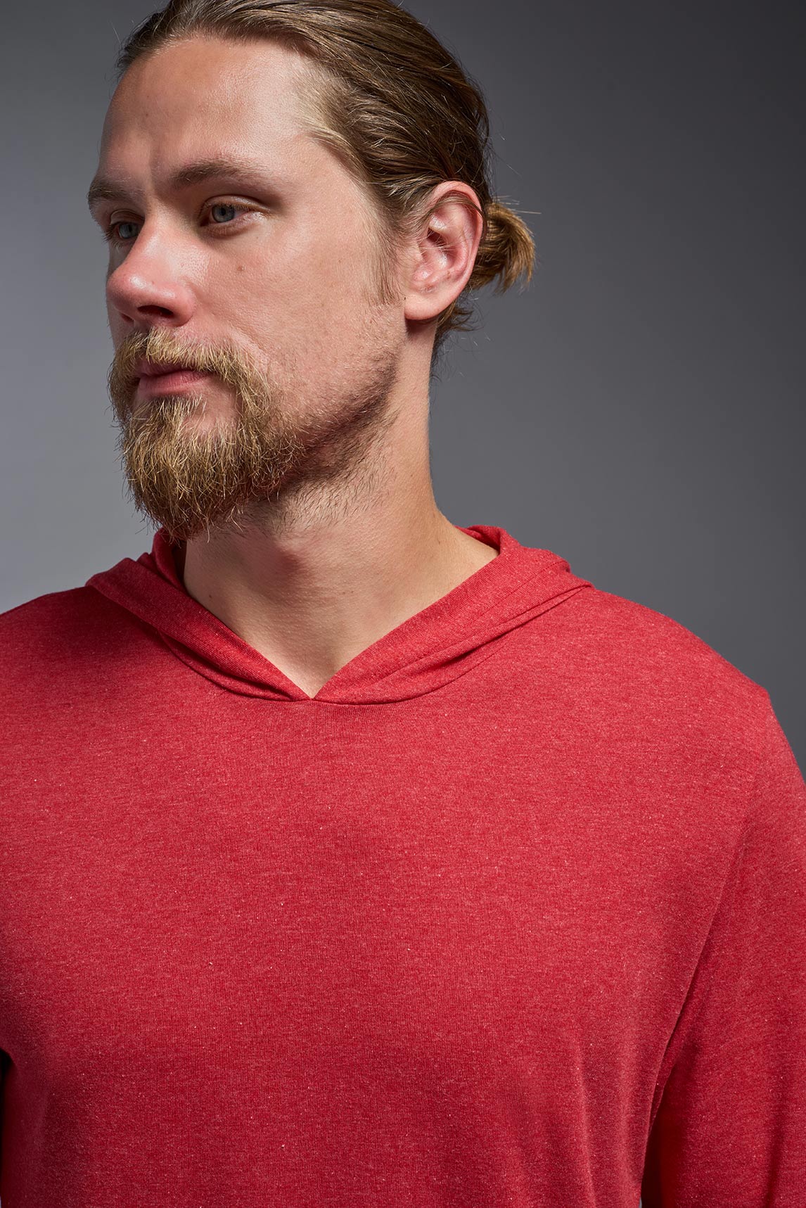 A blonde male model with a beard on a gray background, wearing the men's Heather Hoodie Shirt in the color dark heather red, made out of 88% polyester and 22% treated cotton, showing the relaxed fit from a front closeup collar view. This hoodie shirt is comfortable and made in the USA. #dark-heather-red