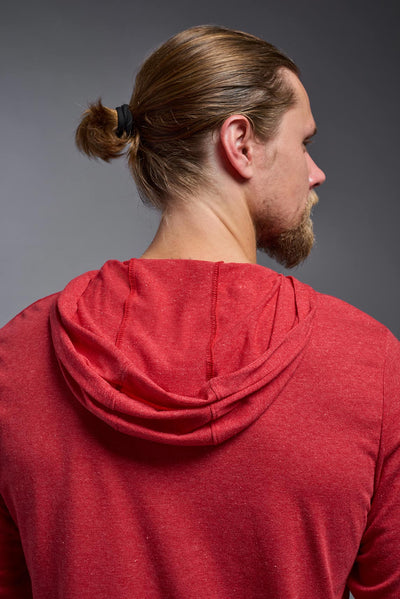 A blonde male model with a beard on a gray background, wearing the men's Heather Hoodie Shirt in the color dark heather red, made out of 88% polyester and 22% treated cotton, showing the relaxed fit from a back closeup hood view. This hoodie shirt is comfortable and made in the USA. #dark-heather-red