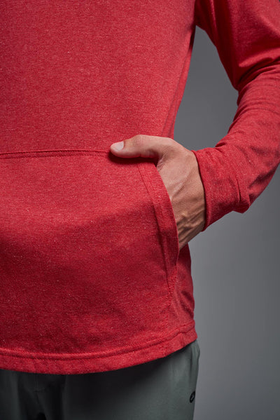 A blonde male model with a beard on a gray background, wearing the men's Heather Hoodie Shirt in the color dark heather red, made out of 88% polyester and 22% treated cotton, showing the relaxed fit from a front closeup pocket view. This hoodie shirt is comfortable and made in the USA. #dark-heather-red