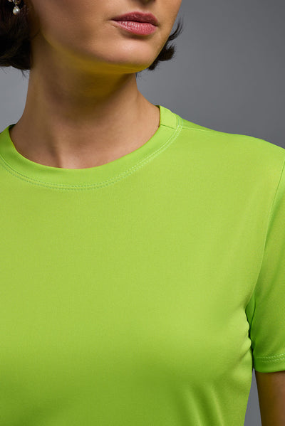 A female model with short brown hair on a gray background, wearing the Women's DriMax Crewneck Expert Tee in the color key lime from a closeup collar front view. This shirt is made in the USA and is quick-drying and moisture-wicking. #color_key-lime