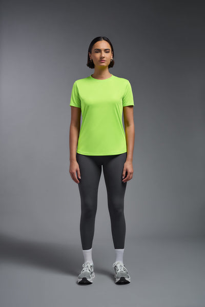 A female model with short brown hair on a gray background, wearing the Women's DriMax Crewneck Expert Tee in the color safety yellow from a full body front view. This shirt is made in the USA and is quick-drying and moisture-wicking. #color_safety-yellow