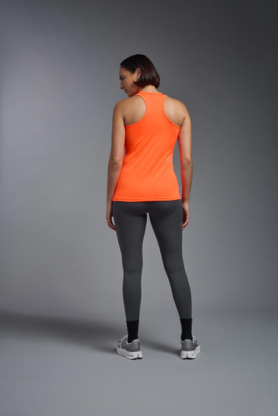 A female model with brown short hair on a gray background, wearing the Women's DrImax Endurance Racerback Tank in the color safety orange from a full body back view. This tank is made in the USA and is quick-drying and moisture-wicking. #color_safety-orange