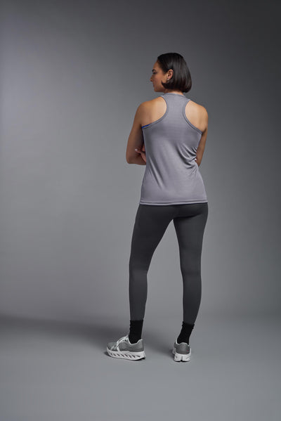 A female model with brown short hair on a gray background, wearing the Women's Drimax Endurance Racerback Tank in the color steel from a full body back view. This tank is made in the USA and is quick-drying and moisture-wicking. #color_steel