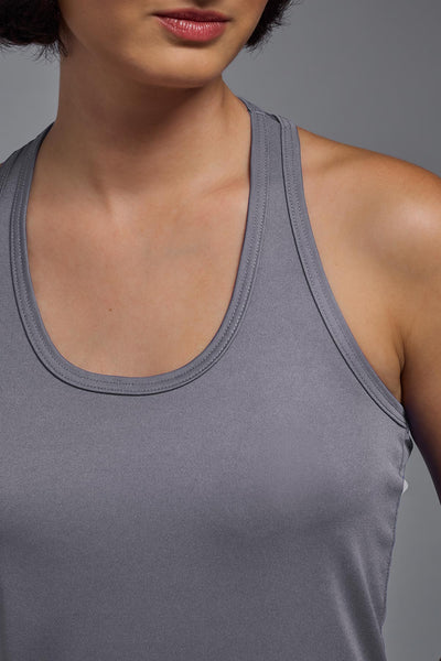 A female model with brown short hair on a gray background, wearing the Women's Drimax Endurance Racerback Tank in the color steel from a closeup collar front view. This tank is made in the USA and is quick-drying and moisture-wicking. #color_steel