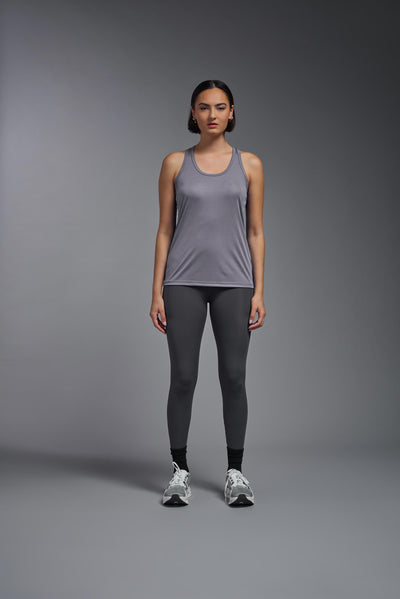 A female model with brown short hair on a gray background, wearing the Women's Drimax Endurance Racerback Tank in the color steel from a full body front view. This tank is made in the USA and is quick-drying and moisture-wicking. #color_steel