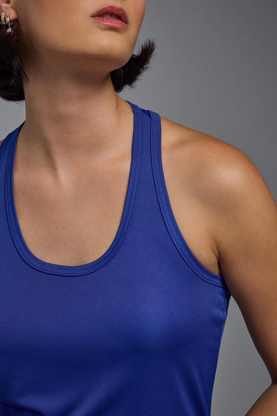 A female model with brown short hair on a gray background, wearing the Women's Drimax Endurance Racerback Tank in the color royal blue from a collar closeup view. This tank is made in the USA and is quick-drying and moisture-wicking. #color_royal-blue