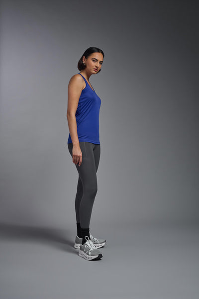 A female model with brown short hair on a gray background, wearing the Women's Drimax Endurance Racerback Tank in the color royal blue from a full body side view. This tank is made in the USA and is quick-drying and moisture-wicking. #color_royal-blue
