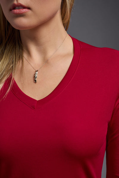 A blonde female model with long straight hair on a gray background, wearing the Women's DriMax™ V-neck Long Sleeve Expert Tee in the color red from a  closeup collar view. This shirt is made in the USA and is quick-drying and moisture-wicking. #color_red