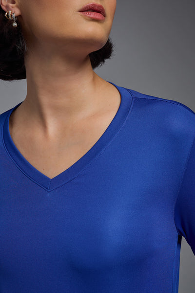 A female model with short brown hair on a gray background, wearing the Women's DriMax™ V-neck Long Sleeve Expert Tee in the color royal blue from a closeup collar front view. This shirt is made in the USA and is quick-drying and moisture-wicking. #color_royal-blue