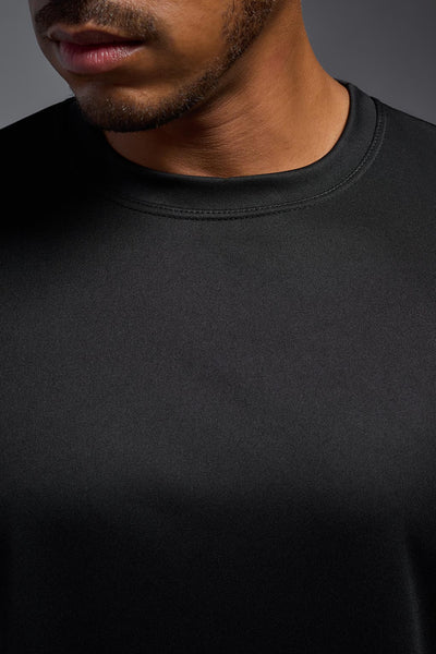 An African American male model with a beard on a gray background, wearing the Men's DriMax Expert Tee Shirt in the color black from a full body collar close-up view. This shirt is made in the USA and is quick-drying and moisture-wicking. #color_black