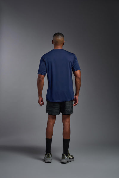 An African American male model with a beard on a gray background, wearing the Men's DriMax Expert Tee Shirt in the color  navy from a full body front view. This shirt is made in the USA and is quick-drying and moisture-wicking. #color_navy