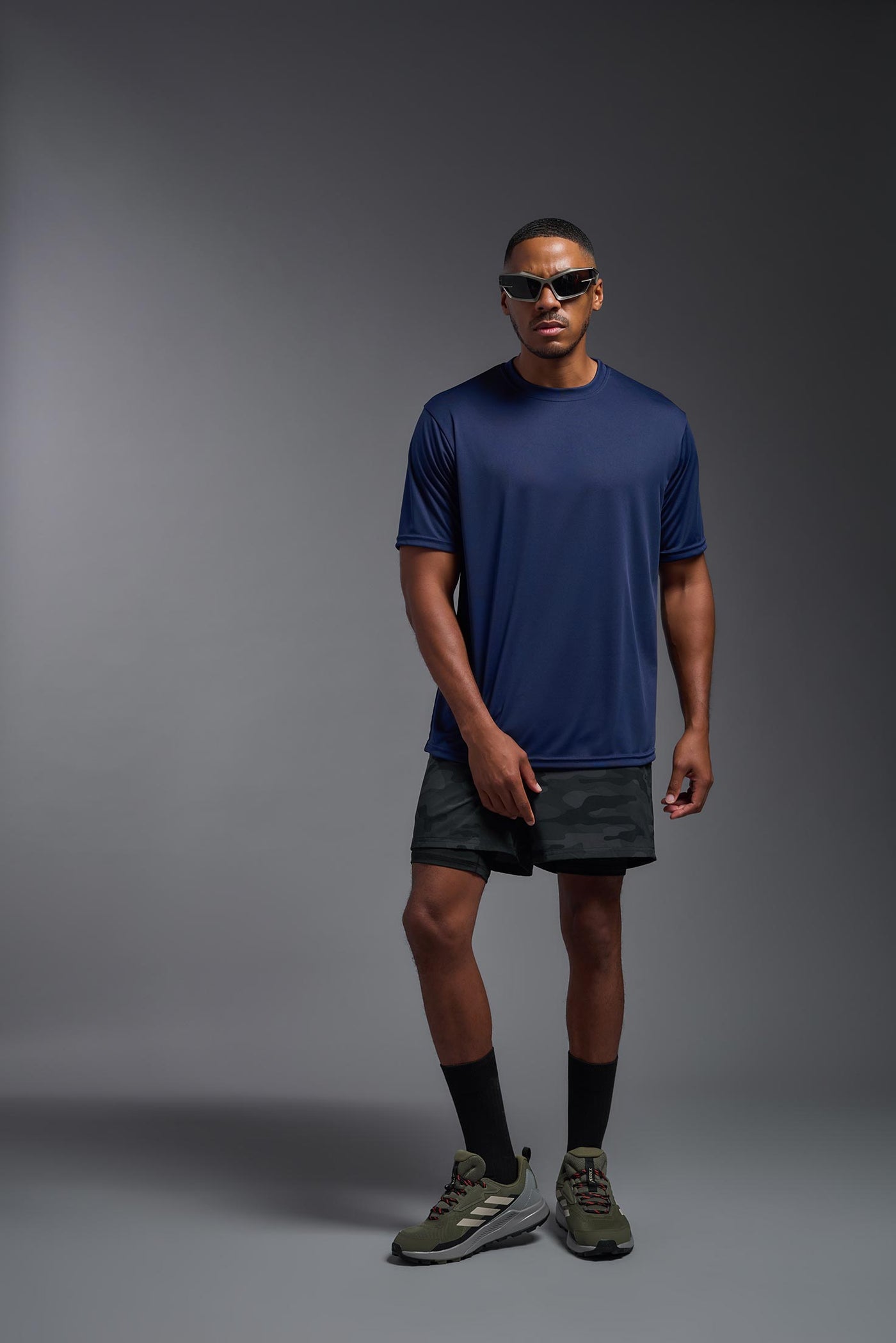 An African American male model with a beard on a gray background, wearing the Men's DriMax Expert Tee Shirt in the color  navy from a full body front view. This shirt is made in the USA and is quick-drying and moisture-wicking. #color_navy