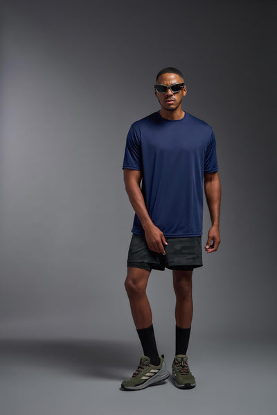 An African American male model with a beard on a gray background, wearing the Men's DriMax Expert Tee Shirt in the color  navy from a full body front view. This shirt is made in the USA and is quick-drying and moisture-wicking. #color_navy