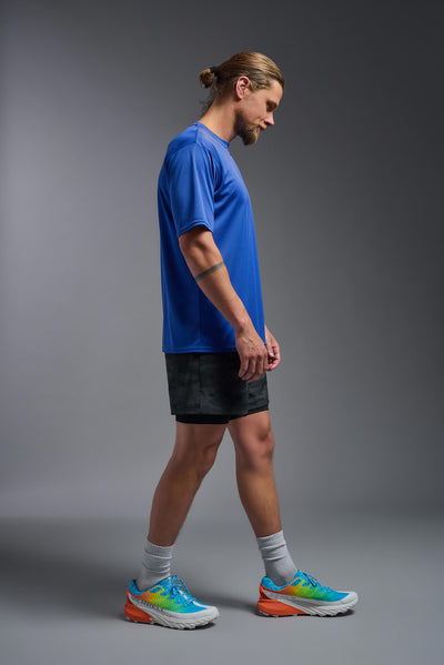A blonde male model with a beard on a gray background, wearing the Men's DriMax Expert Tee Shirt in the color royal blue from a full body side view. This shirt is made in the USA and is quick-drying and moisture-wicking. #color_royal-blue