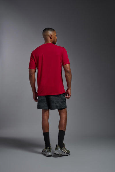 An African American male model with a beard on a gray background, wearing the Men's DriMax Expert Tee Shirt in the color true red from a full body back view. This shirt is made in the USA and is quick-drying and moisture-wicking. #color_true-red