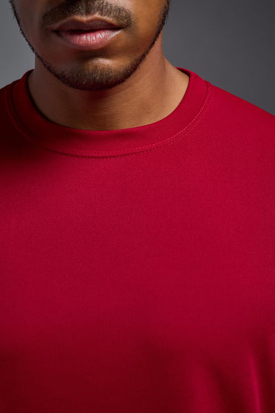 An African American male model with a beard on a gray background, wearing the Men's DriMax Expert Tee Shirt in the color true red from a close-up collar view. This shirt is made in the USA and is quick-drying and moisture-wicking. #color_true-red