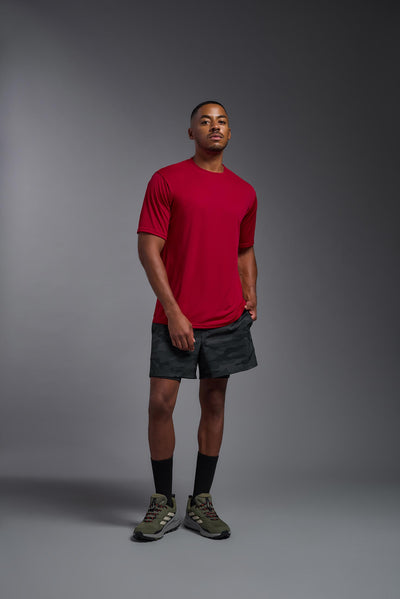 An African American male model with a beard on a gray background, wearing the Men's DriMax Expert Tee Shirt in the color true red from a full body front view. This shirt is made in the USA and is quick-drying and moisture-wicking. #color_true-red