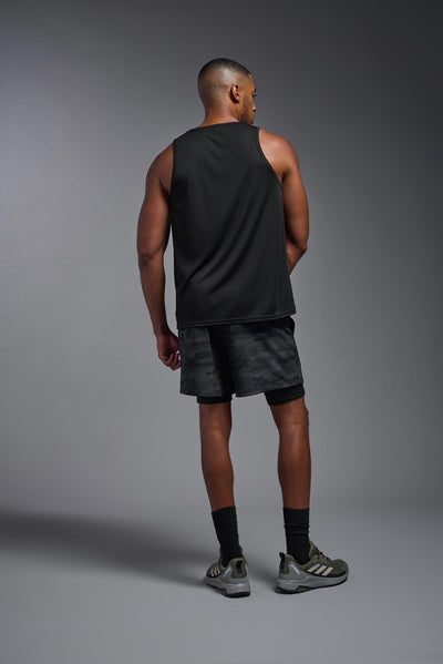 An African American male model with a beard on a gray background, wearing the Men's DriMax Endurance Tank in the color black from a full body back view. This shirt is made in the USA and is quick-drying and moisture-wicking. #color_black