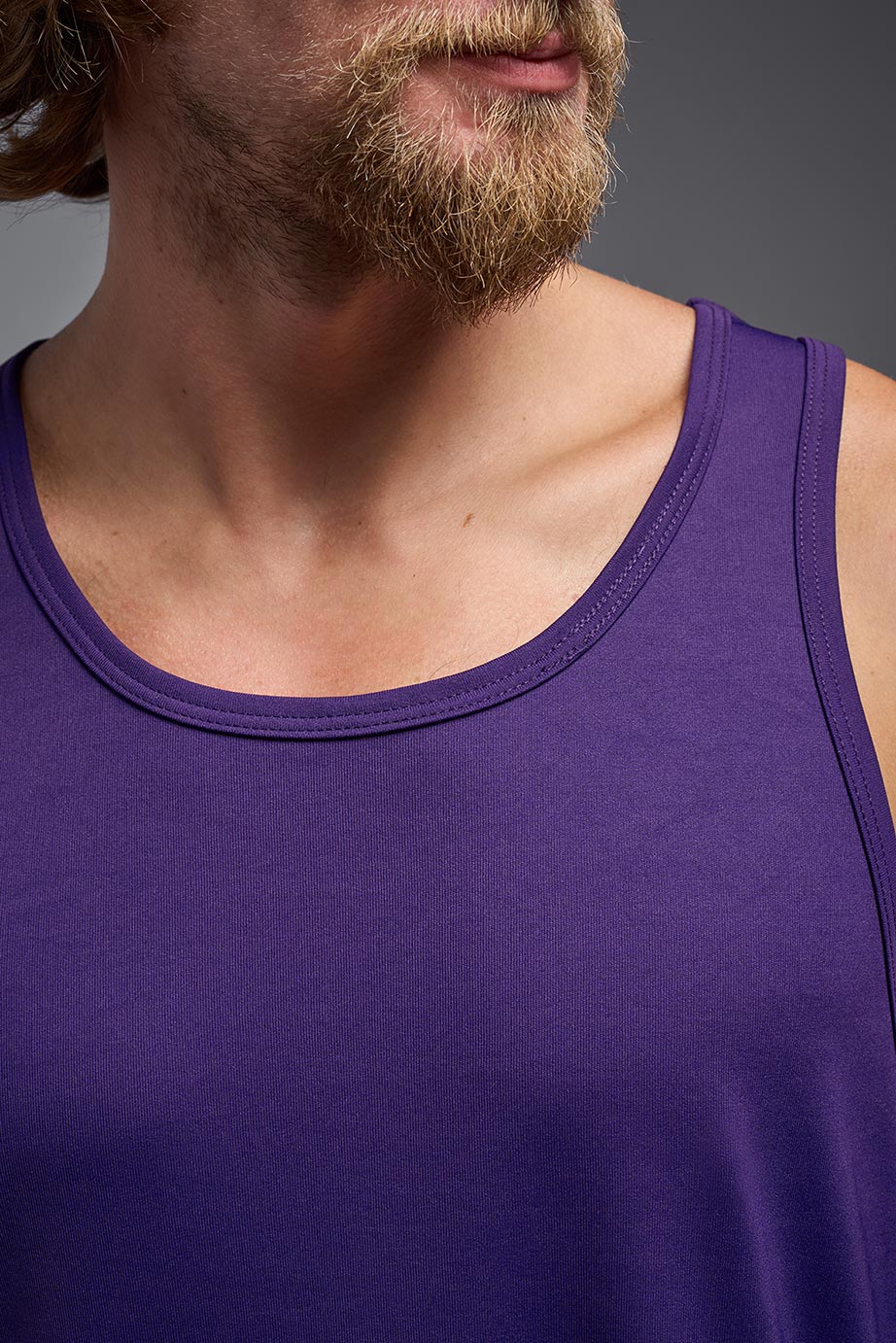 A blonde male model with a beard on a gray background, wearing the Men's DriMax Endurance Tank in the color dark purple from a closeup collar front view. This shirt is made in the USA and is quick-drying and moisture-wicking. #color_dark-purple