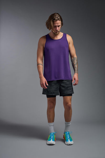 A blonde male model with a beard on a gray background, wearing the Men's DriMax Endurance Tank in the color dark purple from a full body front view. This shirt is made in the USA and is quick-drying and moisture-wicking. #color_dark-purple