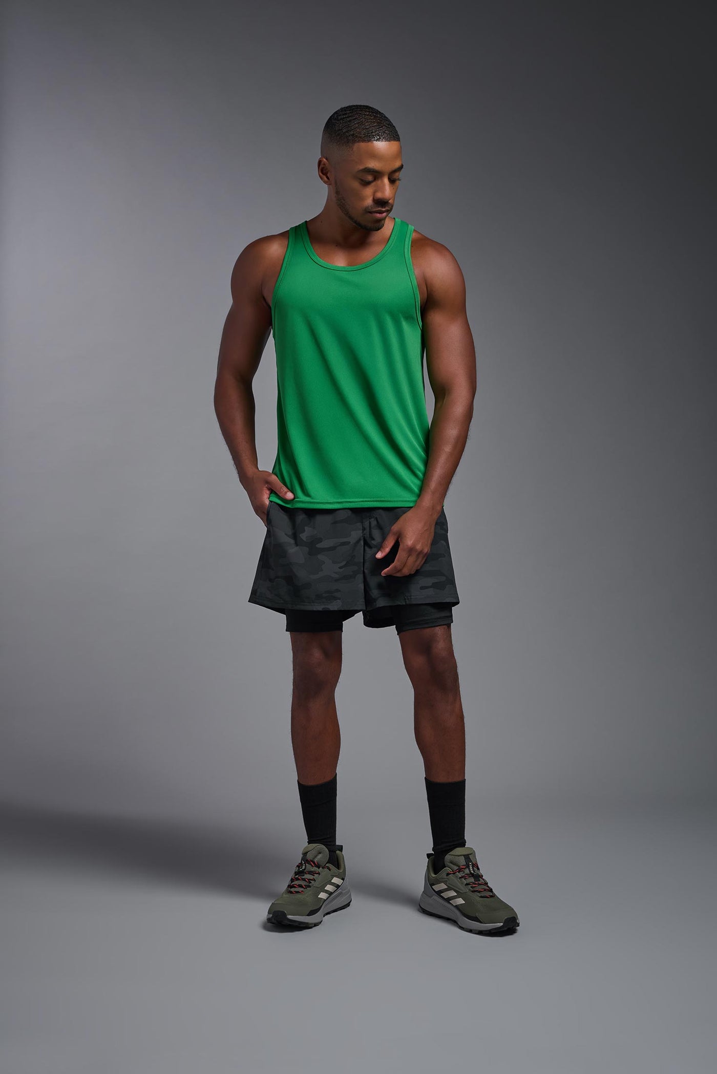 An African American male model with a beard on a gray background, wearing the Men's DriMax Endurance Tank in the color kelly greenfrom a full body front view. This shirt is made in the USA and is quick-drying and moisture-wicking. #color_kelly-green