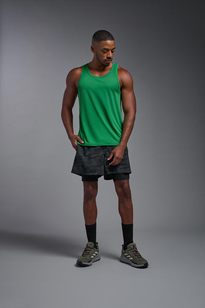 An African American male model with a beard on a gray background, wearing the Men's DriMax Endurance Tank in the color kelly greenfrom a full body front view. This shirt is made in the USA and is quick-drying and moisture-wicking. #color_kelly-green