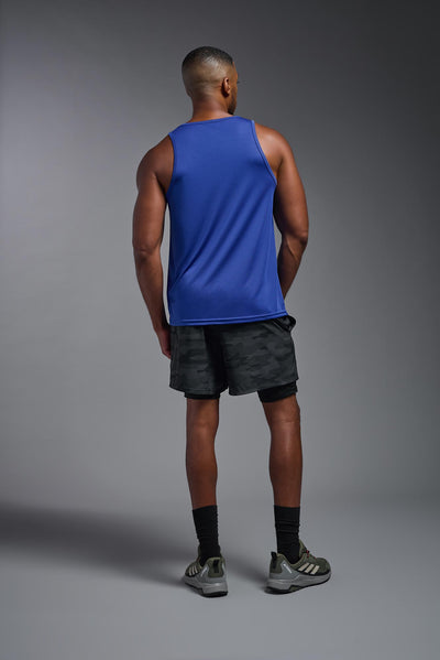 An African American male model with a beard on a gray background, wearing the Men's DriMax Endurance Tank in the color royal blue from a full body back view. This shirt is made in the USA and is quick-drying and moisture-wicking. #color_royal-blue