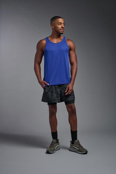 An African American male model with a beard on a gray background, wearing the Men's DriMax Endurance Tank in the color royal blue from a full body front view. This shirt is made in the USA and is quick-drying and moisture-wicking. #color_royal-blue