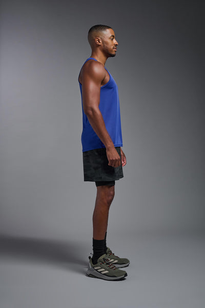 An African American male model with a beard on a gray background, wearing the Men's DriMax Endurance Tank in the color royal blue from a full body side view. This shirt is made in the USA and is quick-drying and moisture-wicking. #color_royal-blue