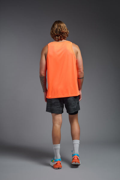 A blonde male model with a beard on a gray background, wearing the Men's DriMax Endurance Tank in the color safety orange from a full body back view. This shirt is made in the USA and is quick-drying and moisture-wicking. #color_safety-orange
