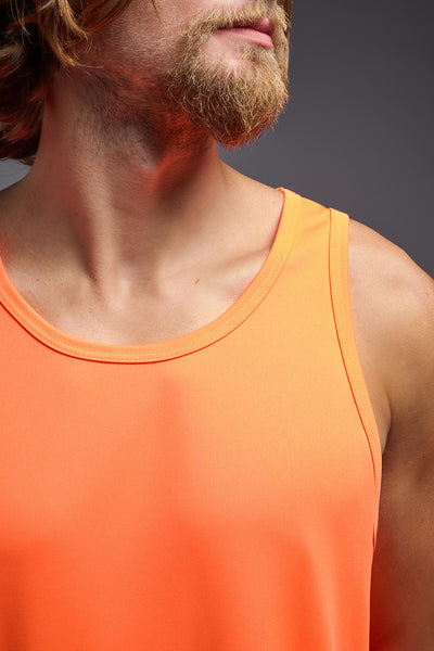 A blonde male model with a beard on a gray background, wearing the Men's DriMax Endurance Tank in the color safety orange from a closeup collar front view. This shirt is made in the USA and is quick-drying and moisture-wicking. #color_safety-orange