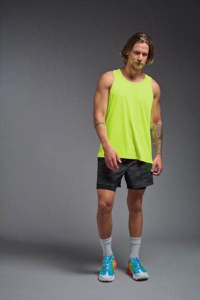 A blonde male model with a beard on a gray background, wearing the Men's DriMax Endurance Tank in the color safety yellow from a full body front view. This shirt is made in the USA and is quick-drying and moisture-wicking. #color_safety-yellow