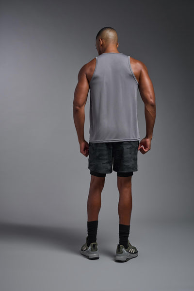 An African American male model with a beard on a gray background, wearing the Men's DriMax Endurance Tank in the color steel gray from a full body back view. This shirt is made in the USA and is quick-drying and moisture-wicking. #color_steel