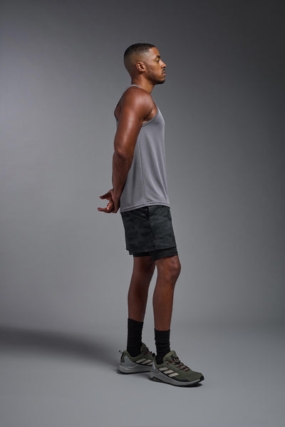 An African American male model with a beard on a gray background, wearing the Men's DriMax Endurance Tank in the color steel gray from a full body side view. This shirt is made in the USA and is quick-drying and moisture-wicking. #color_steel