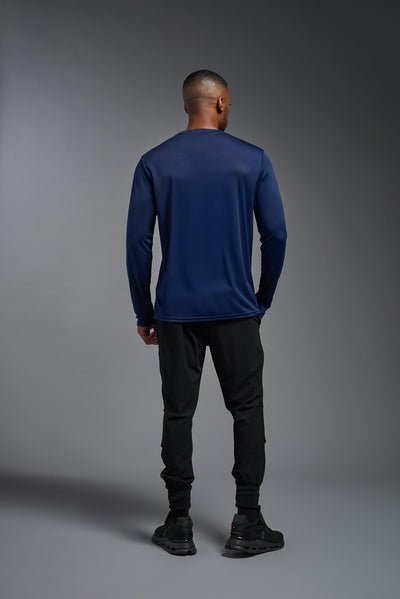 An African American male model with a beard on a gray background, wearing the Men's DriMax Long Sleeve Expert Shirt in the color navy from a full body back view. This shirt is made in the USA and is quick-drying and moisture-wicking. #color_navy