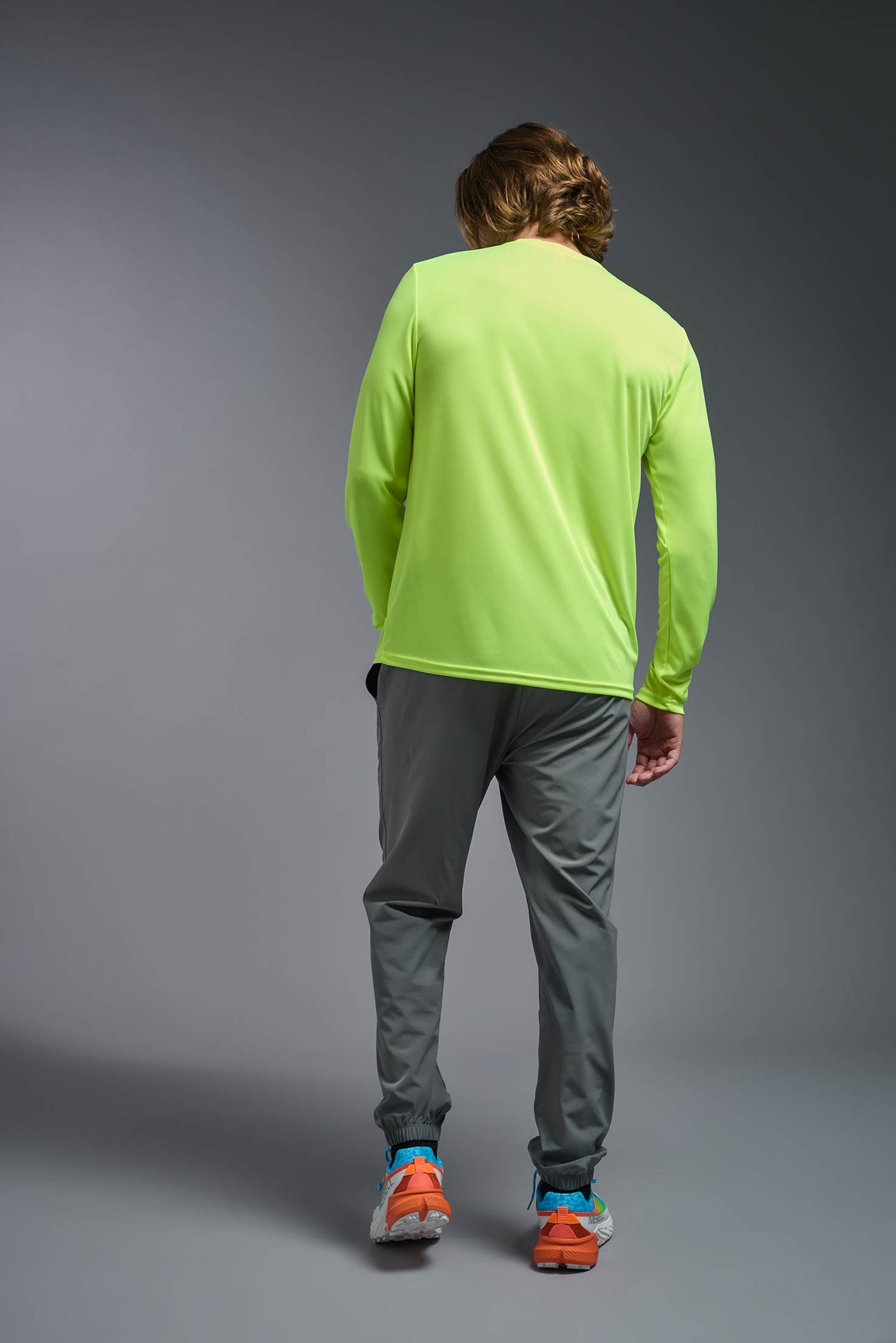 An African American male model with a beard on a gray background, wearing the Men's DriMax Long Sleeve Expert Shirt in the color safety yellow from a full body back view. This shirt is made in the USA and is quick-drying and moisture-wicking. #color_safety-yellow