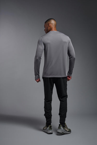 An African American male model with a beard on a gray background, wearing the Men's DriMax Long Sleeve Expert Shirt in the color steel from a full body back view. This shirt is made in the USA and is quick-drying and moisture-wicking. #color_steel