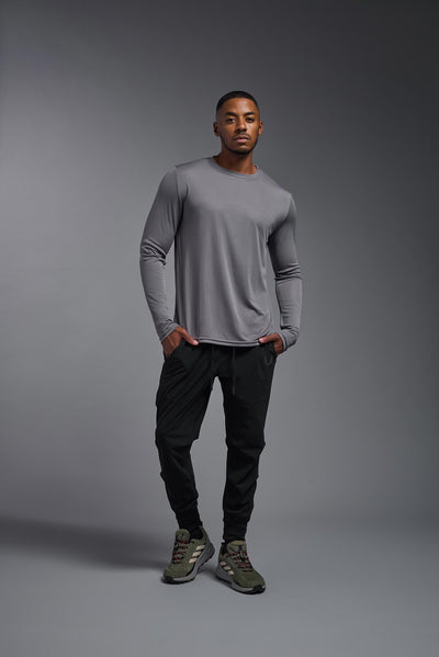 An African American male model with a beard on a gray background, wearing the Men's DriMax Long Sleeve Expert Shirt in the color steel from a full body front view. This shirt is made in the USA and is quick-drying and moisture-wicking. #color_steel