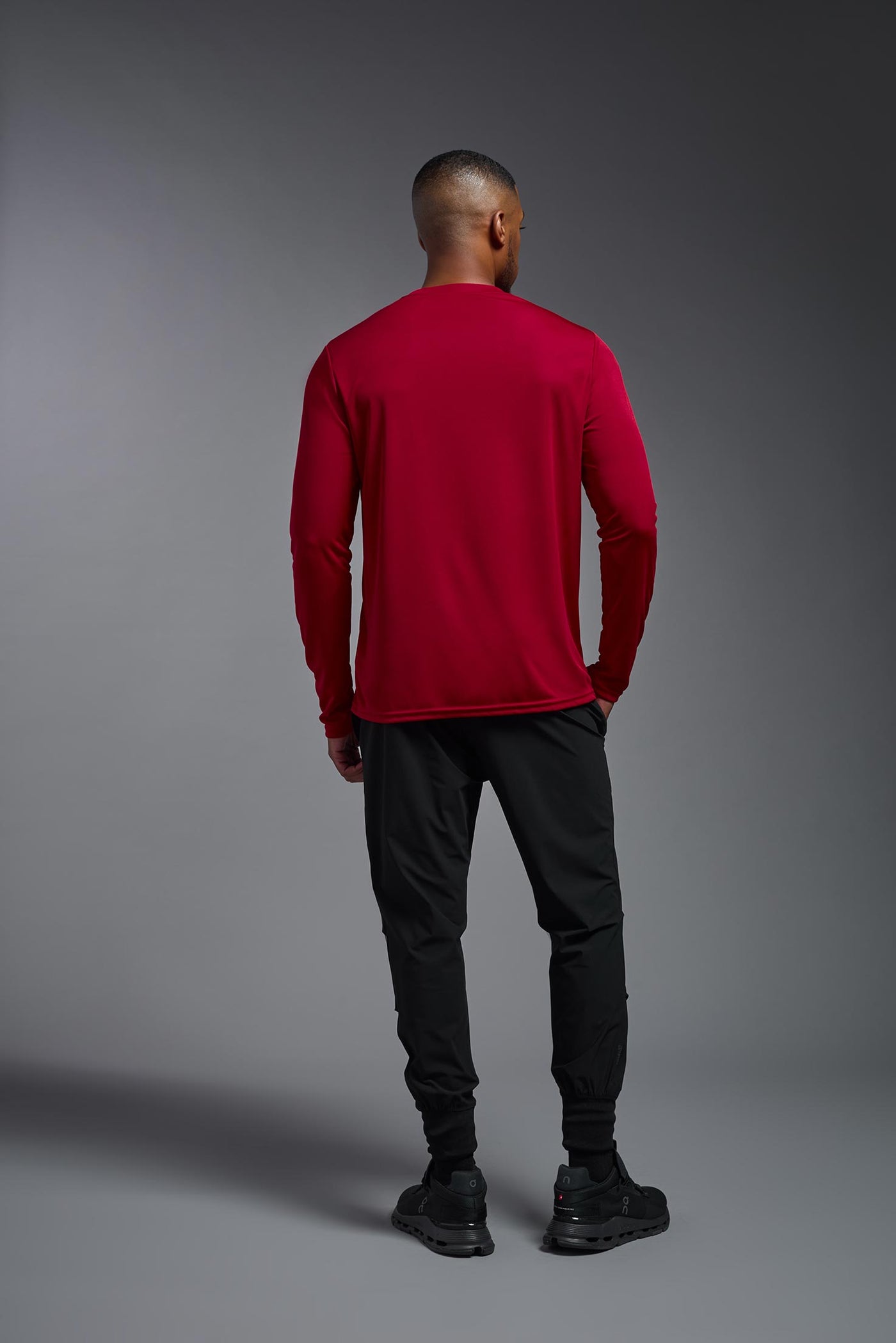 A blonde male model with a beard on a gray background, wearing the Men's DriMax Long Sleeve Expert Shirt in the color true red from a full body front view. This shirt is made in the USA and is quick-drying and moisture-wicking. #color_true-red