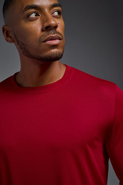 An African American male model with a beard on a gray background, wearing the Men's DriMax Long Sleeve Expert Shirt in the color true red from a close-up collar view. This shirt is made in the USA and is quick-drying and moisture-wicking. #color_true-red