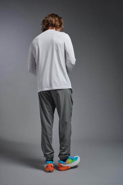 A blonde male model with a beard on a gray background, wearing the Men's DriMax Long Sleeve Expert Shirt in the color white from a full body back view. This shirt is made in the USA and is quick-drying and moisture-wicking. #color_white
