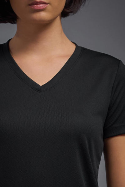 A female model with brown short hair on a gray background, wearing the Women's Oxymesh™ V-neck Tech Tee in the color black from a closeup collar front view. This shirt is made in the USA and is quick-drying and moisture-wicking. #color_black