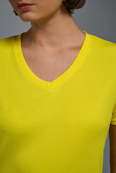 A female model with brown short hair on a gray background, wearing the Women's Oxymesh™ V-neck Tech Tee in the color bright yellow from a closeup collar front view. This shirt is made in the USA and is quick-drying and moisture-wicking. #color_bright-yellow
