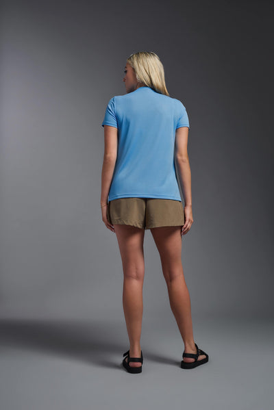 A blonde female model with long straight hair on a gray background, wearing the Women's Oxymesh™ V-neck Tech Tee in the color carolina blue from a full body back view. This shirt is made in the USA and is quick-drying and moisture-wicking. #color_carolina-blue
