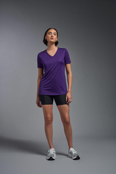 A female model with short brown hair on a gray background, wearing the Women's Oxymesh™ V-neck Tech Tee in the color dark purple from a full body front view. This shirt is made in the USA and is quick-drying and moisture-wicking. #color_dark-purple