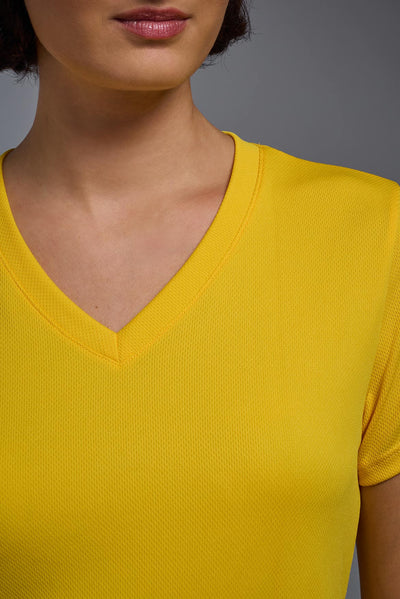 A female model with brown short hair on a gray background, wearing the Women's Oxymesh™ V-neck Tech Tee in the color gold from a closeup collar front view. This shirt is made in the USA and is quick-drying and moisture-wicking. #color_gold