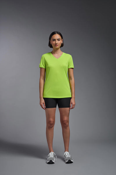 A female model with brown short hair on a gray background, wearing the Women's Oxymesh™ V-neck Tech Tee in the color key lime from a full body front view. This shirt is made in the USA and is quick-drying and moisture-wicking. #color_key-lime