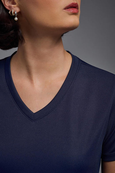 A female model with brown short hair on a gray background, wearing the Women's Oxymesh™ V-neck Tech Tee in the color navy blue from a closeup collar front view. This shirt is made in the USA and is quick-drying and moisture-wicking. #color_navy-blue