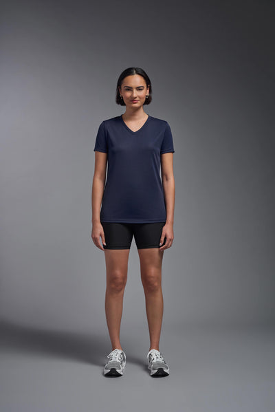 A female model with brown short hair on a gray background, wearing the Women's Oxymesh™ V-neck Tech Tee in the color navy blue from a full body front view. This shirt is made in the USA and is quick-drying and moisture-wicking. #color_navy-blue
